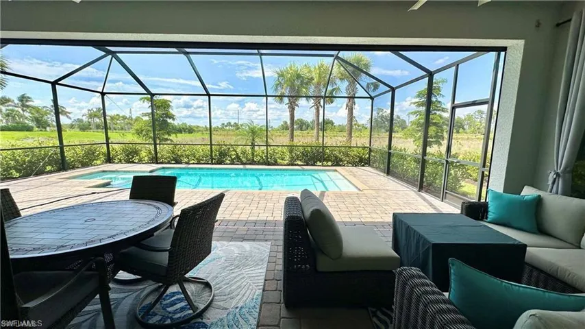 View of swimming pool with glass enclosure and a patio area