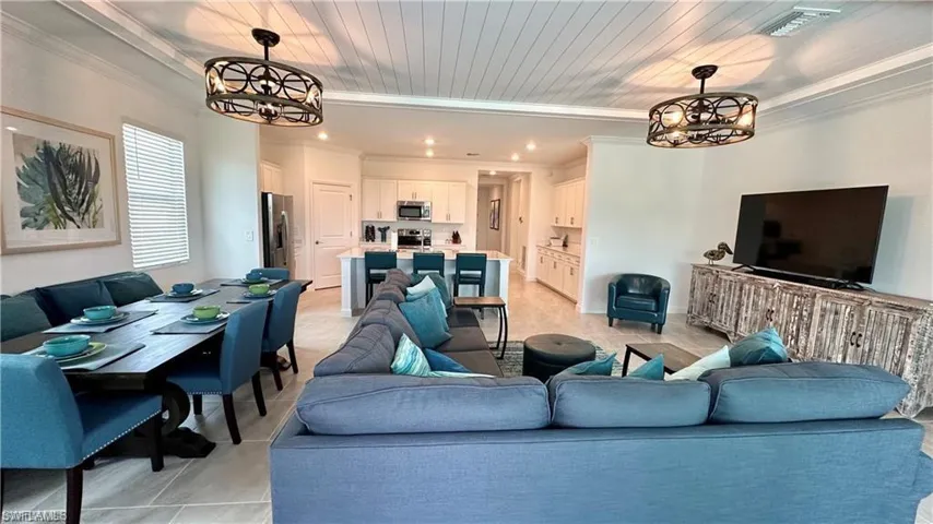 Living room featuring ornamental molding, light tile flooring, and a chandelier