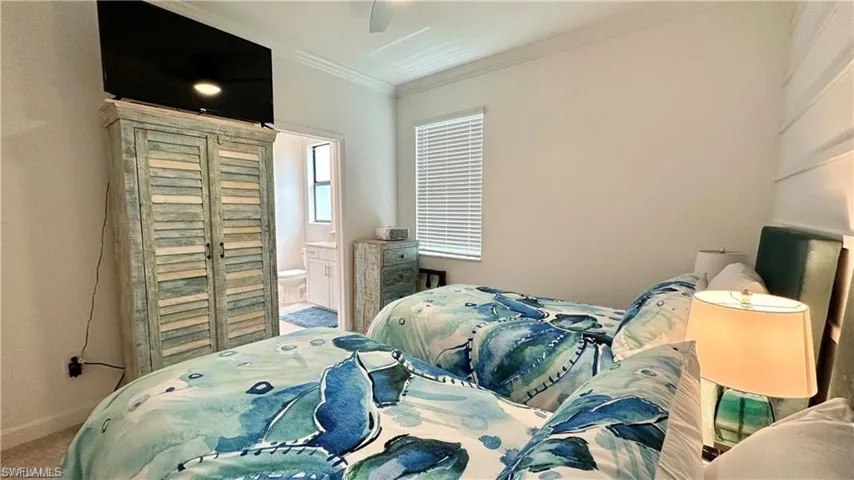 Bedroom featuring connected bathroom, ornamental molding, carpet floors, and ceiling fan