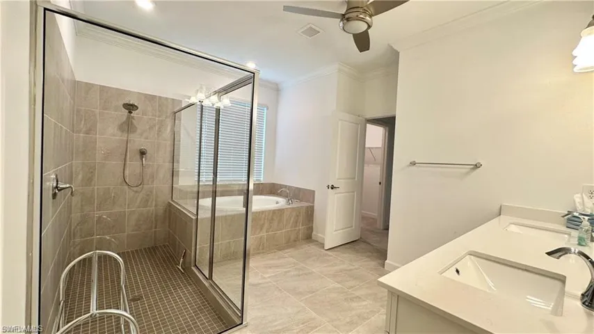 Bathroom featuring ceiling fan, tile flooring, double vanity, and plus walk in shower