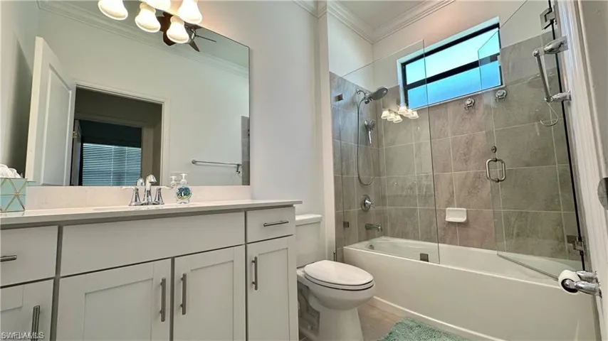 Full bathroom featuring enclosed tub / shower combo, ornamental molding, vanity, and toilet