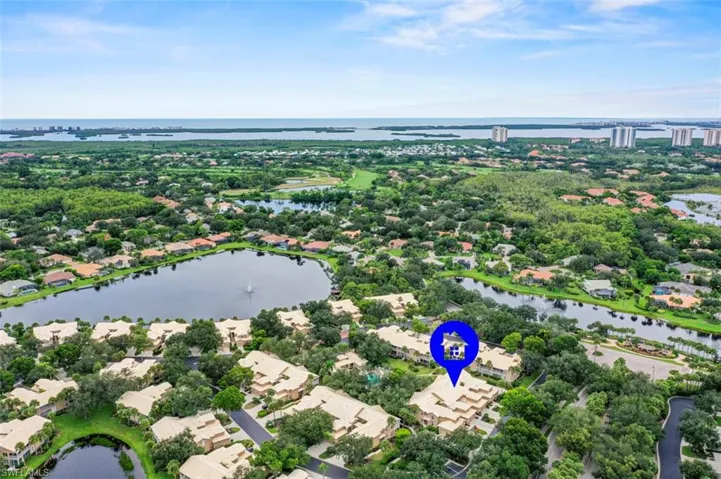 Aerial perspective of a multi-unit residential complex featuring tile roofing and lush landscaping, situated within a coastal community