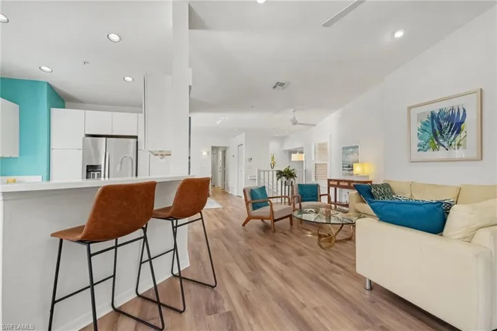 Open-concept interior featuring wood-finish flooring, recessed lighting, and a kitchen island with stone countertop