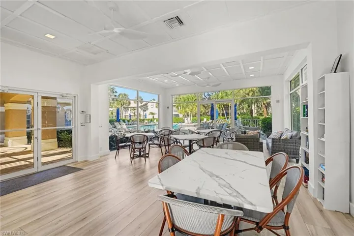 Expansive room featuring a coffered ceiling, wood-finish flooring, floor-to-ceiling windows, and white built-in shelving