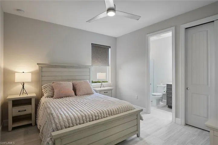 Bedroom featuring ceiling fan, ensuite bathroom, and light hardwood / wood-style floors
