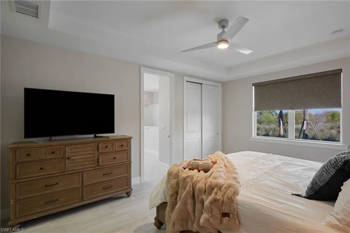 Bedroom with ceiling fan, a closet, and a raised ceiling