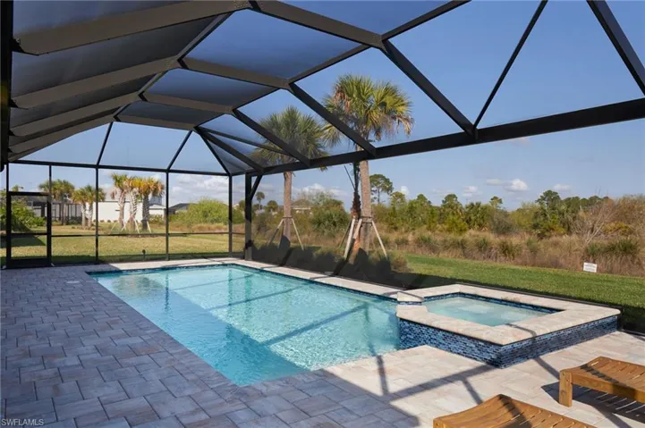 View of swimming pool with an in ground hot tub, a lanai, a patio area, and a lawn
