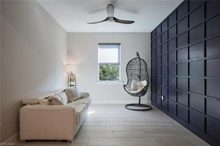 Den with decorative accent wall ceiling fan