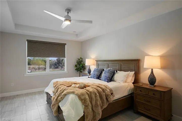 Bedroom with a raised ceiling and ceiling fan