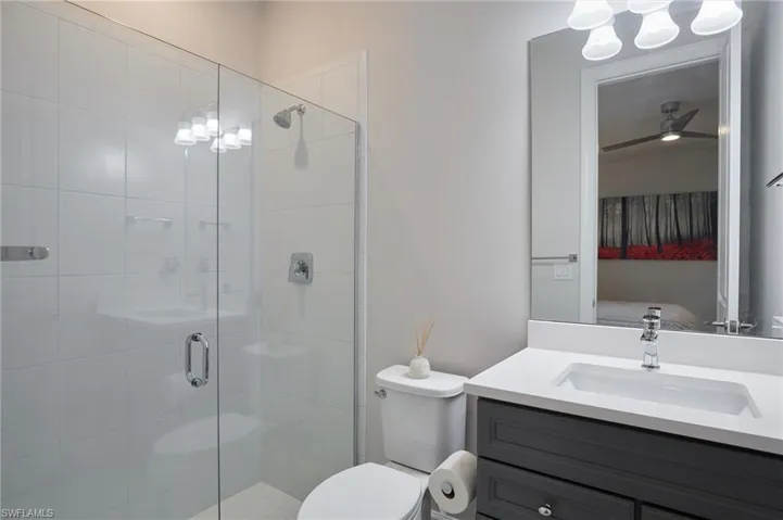 Bathroom with toilet, vanity, and a shower with shower door
