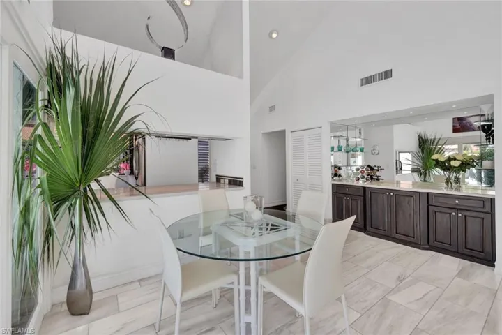 Tiled dining room featuring high vaulted ceiling