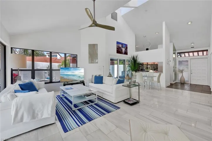 Living room featuring high vaulted ceiling, ceiling fan, light tile patterned floors, and plenty of natural light