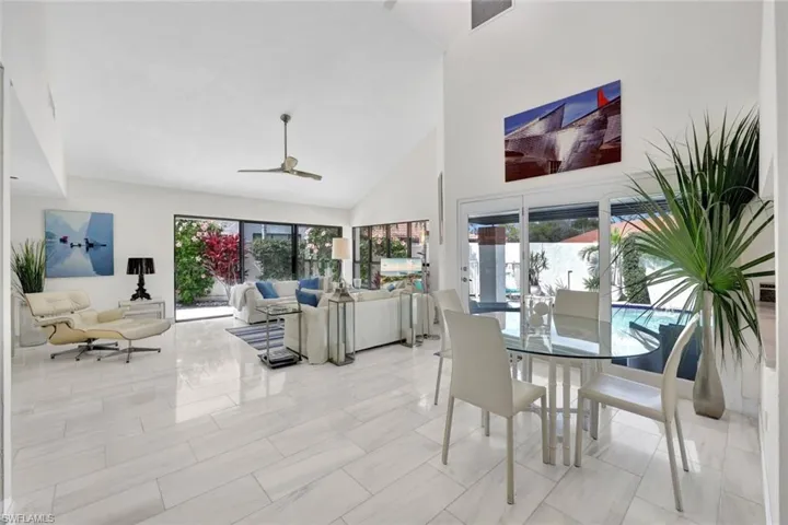 Tiled dining room with ceiling fan and high vaulted ceiling