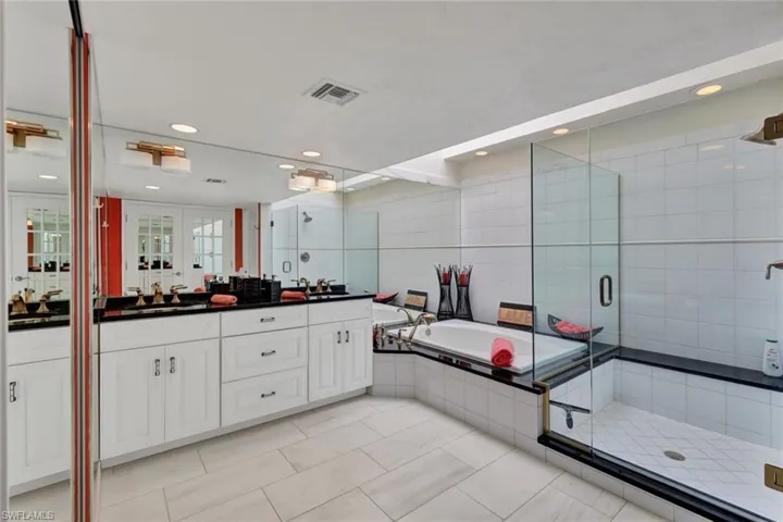 Bathroom featuring plus walk in shower, tile patterned flooring, vanity, and tile walls
