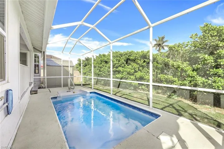 View of swimming pool with a patio, a lanai, ceiling fan, and a shed