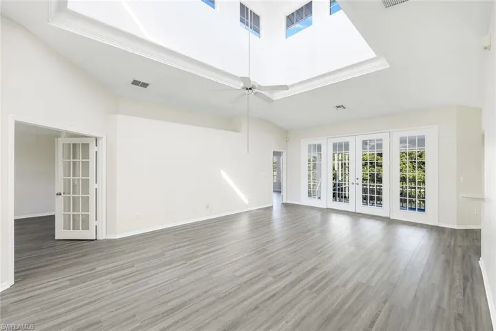 Unfurnished living room featuring ceiling fan, a towering ceiling, and plenty of natural light
