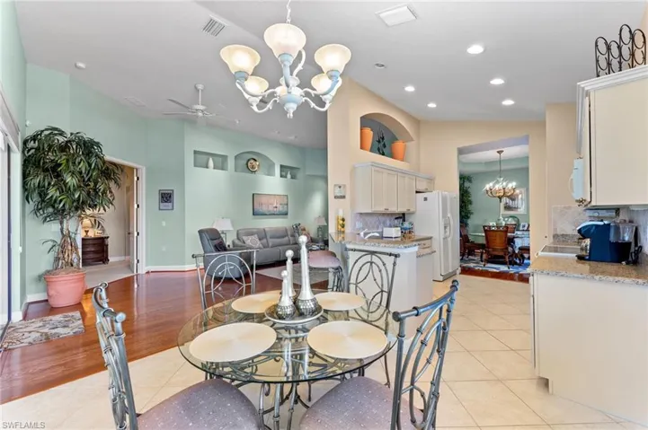 Dining area featuring visible vents, light tile patterned flooring, vaulted ceiling, and ceiling fan with notable chandelier