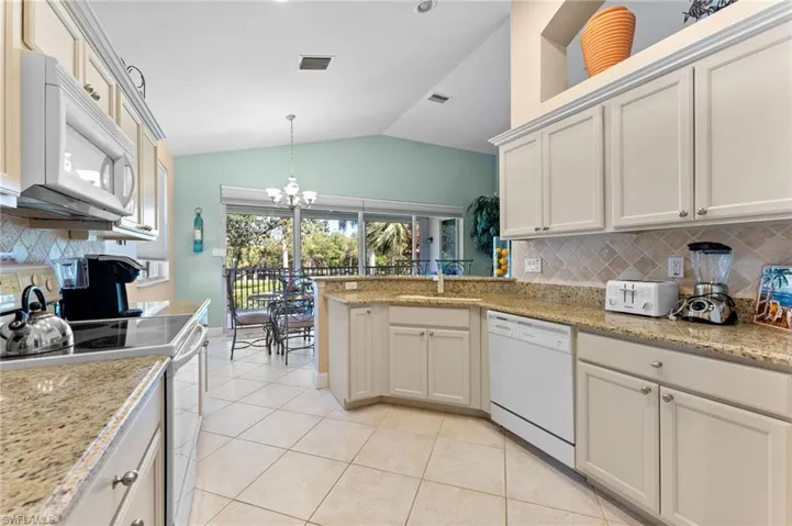 Kitchen featuring white appliances, light tile patterned floors, visible vents, a sink, and a chandelier