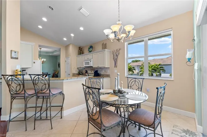Dining space with light tile patterned floors, visible vents, lofted ceiling, recessed lighting, and a notable chandelier