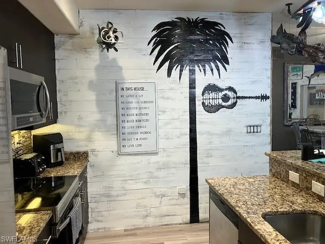 Kitchen with dark stone counters, stainless steel appliances, and light wood-style floors