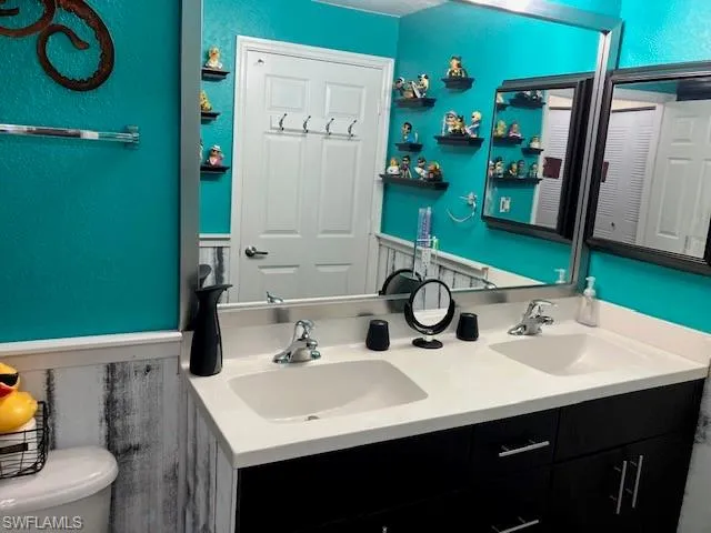 Bathroom featuring a textured wall and double vanity