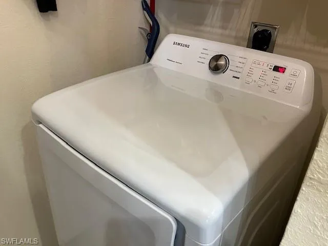 Laundry view of washer / dryer and a textured wall
