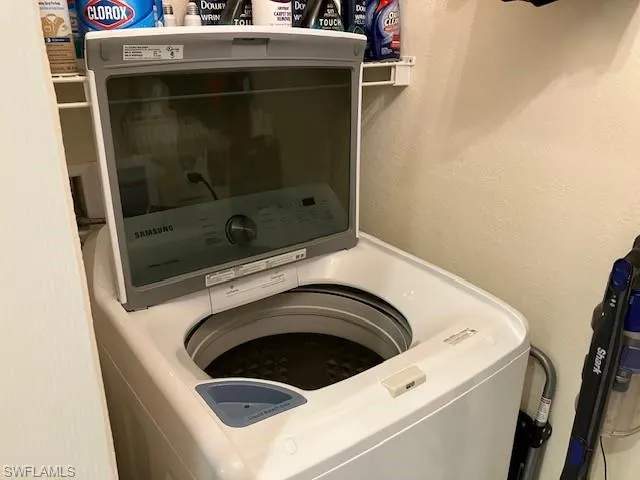 Laundry room featuring a textured wall and washer / dryer