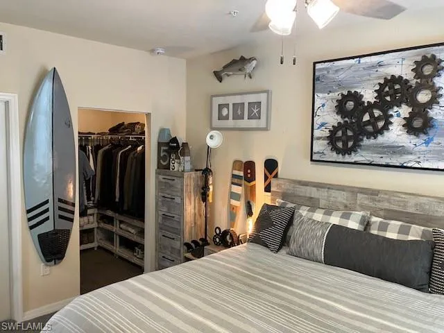 Bedroom with dark carpet, ceiling fan, and a spacious closet