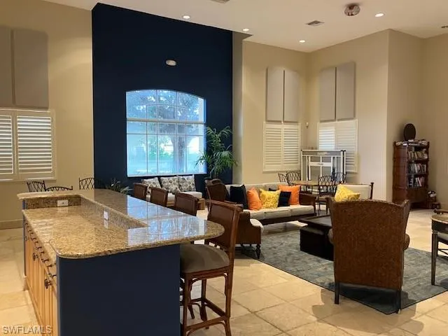 Kitchen featuring a kitchen breakfast bar, a towering ceiling, light stone counters, recessed lighting, and a kitchen island