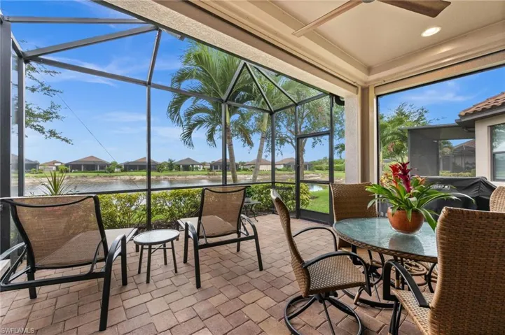 Screened lanai featuring brick paver flooring, a vaulted screen enclosure, and a ceiling fan