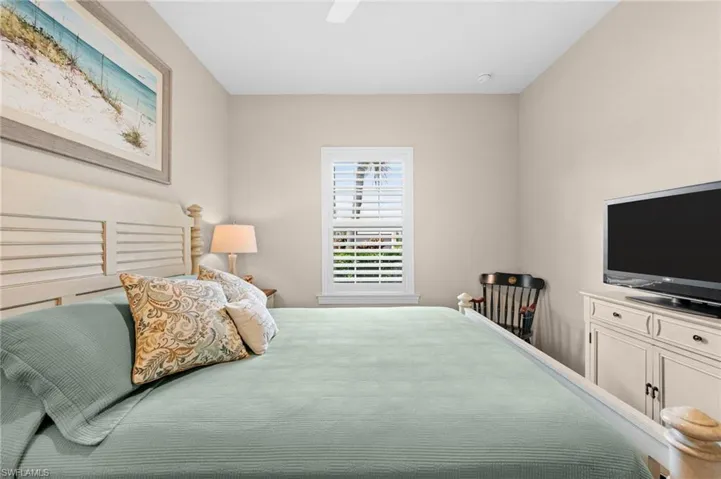 Spacious room featuring neutral painted walls, a window with white plantation shutters, and a white ceiling fan