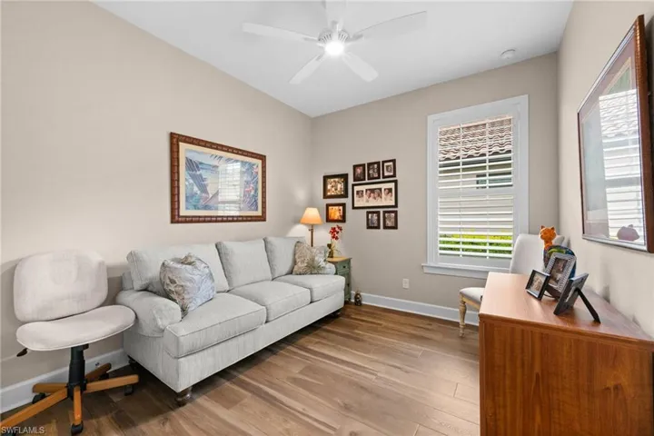 Room featuring wood-finish flooring, neutral wall paint, and a white ceiling fan
