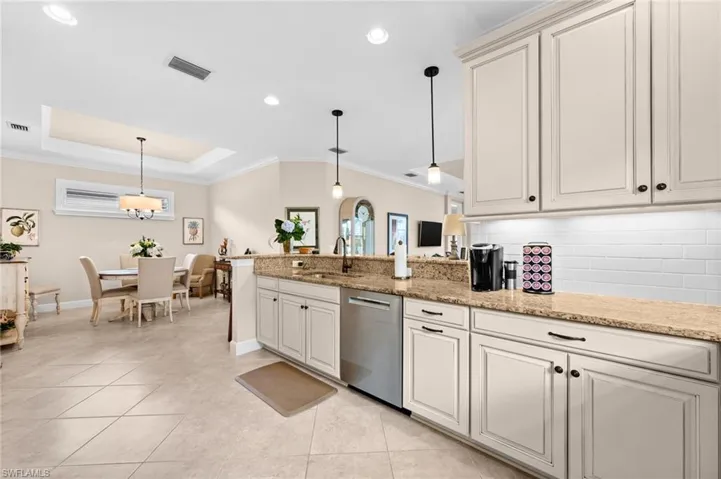 Kitchen featuring cream-colored cabinetry, stainless steel dishwasher, granite countertops, white subway tile backsplash, and recessed lighting