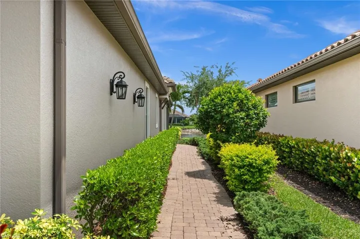 Brick paver pathway bordered by manicured hedges
