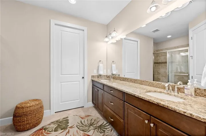 Bathroom featuring a double vanity with granite countertops, undermount sinks, and wood cabinetry