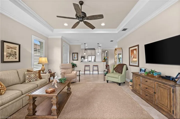 Spacious living area featuring a tray ceiling with recessed lighting and a ceiling fan