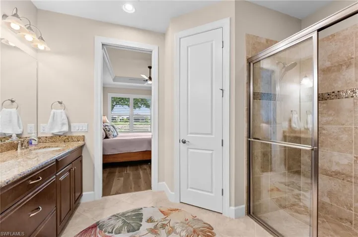 Spacious bathroom featuring a glass-enclosed shower with tiled walls, a vanity with a granite-style countertop, and a built-in recessed light fixture