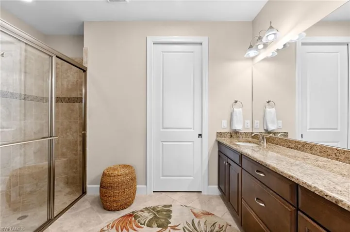 Spacious bathroom featuring a glass-enclosed shower with tiled walls and decorative accent band