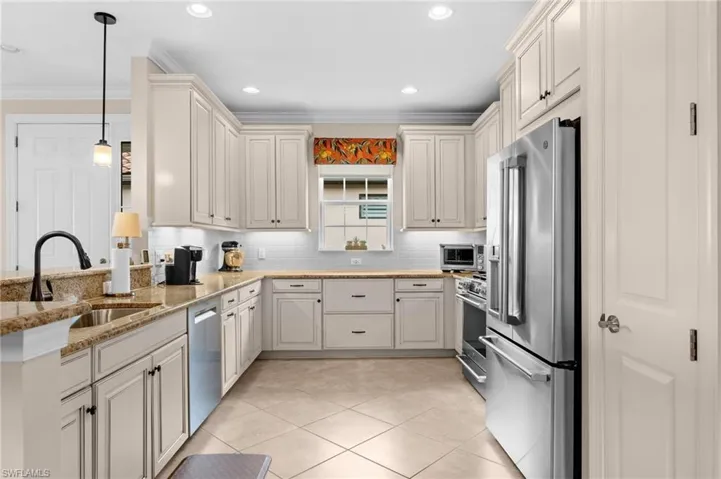 Kitchen featuring light-toned cabinetry, granite countertops, stainless steel appliances, a white subway tile backsplash, and a sink with a matte black faucet