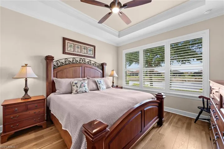 Spacious room featuring wood-finish flooring, a tray ceiling, and a ceiling fan