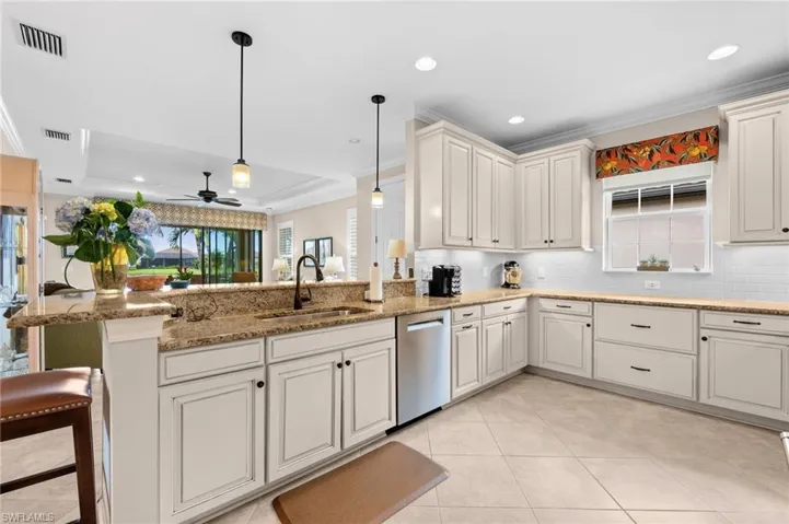 Gourmet kitchen featuring light-toned cabinetry, granite countertops, and a subway tile backsplash