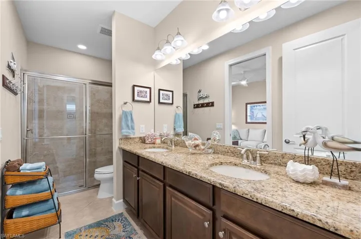 Bathroom featuring a dual vanity with a patterned countertop and undermount sinks