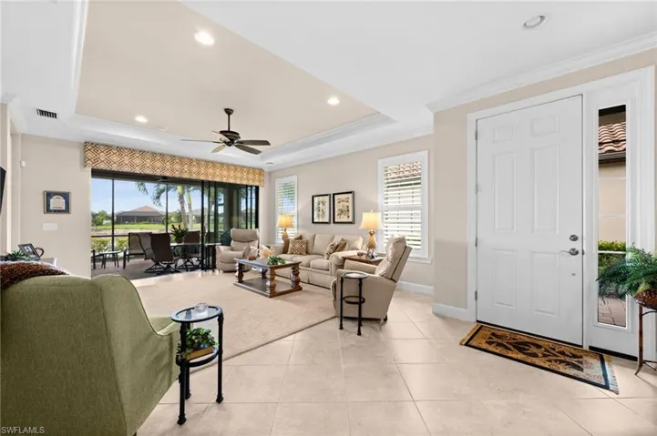 Bright living area featuring large format tile flooring, crown molding, and recessed lighting