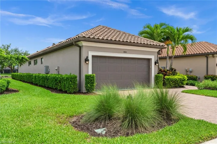 Neutral-toned exterior with a tile roof, an integrated garage, and a paver driveway