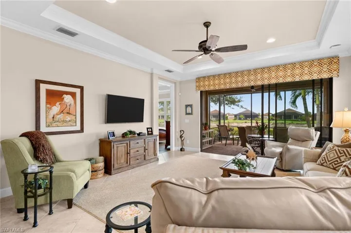 Living area featuring tray ceilings, recessed lighting, and tile flooring extending to a screened lanai