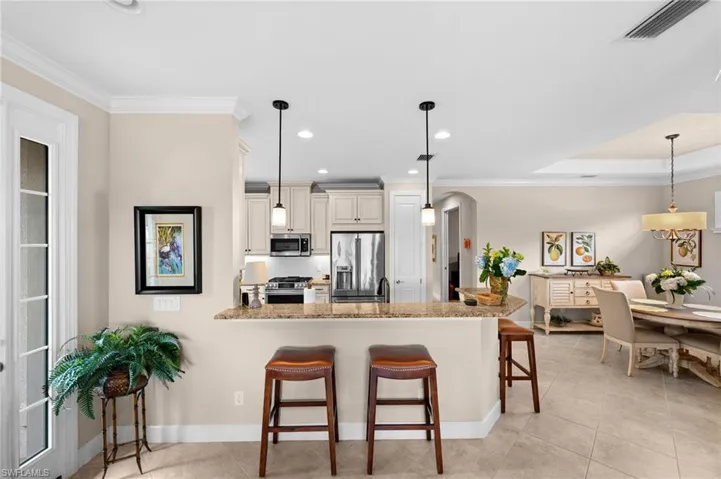 Kitchen featuring light cabinetry, stainless steel appliances, and a breakfast bar with granite-finish countertop