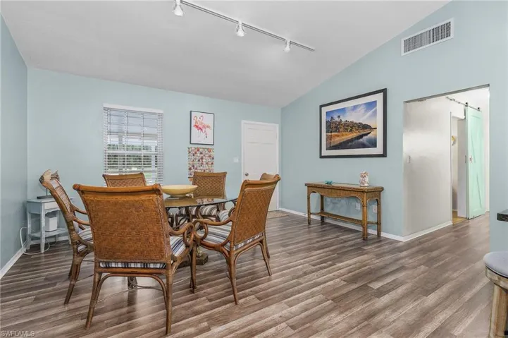 Dining room with rail lighting, wood finished floors, and lofted ceiling