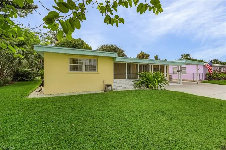 View of front facade featuring stucco siding, a front lawn, a sunroom, and driveway