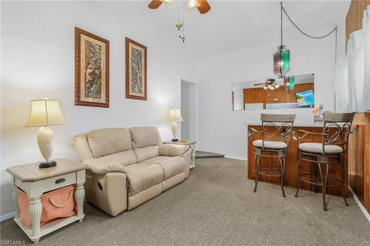 Carpeted living area featuring a ceiling fan and baseboards