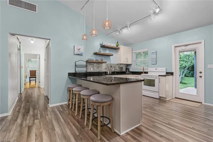 Kitchen featuring rail lighting, white electric stove, wood finished floors, and open shelves